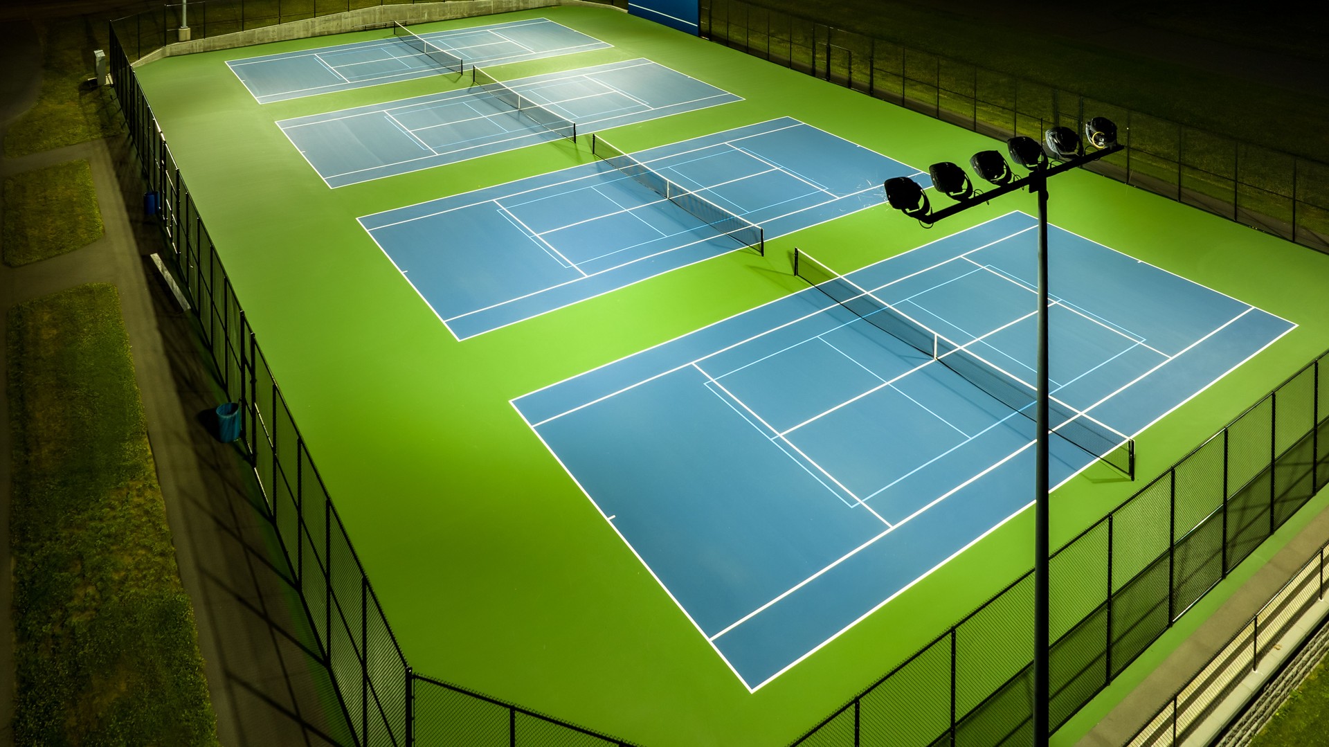 Evening aerial photo of outdoor tennis courts with pickleball lines.