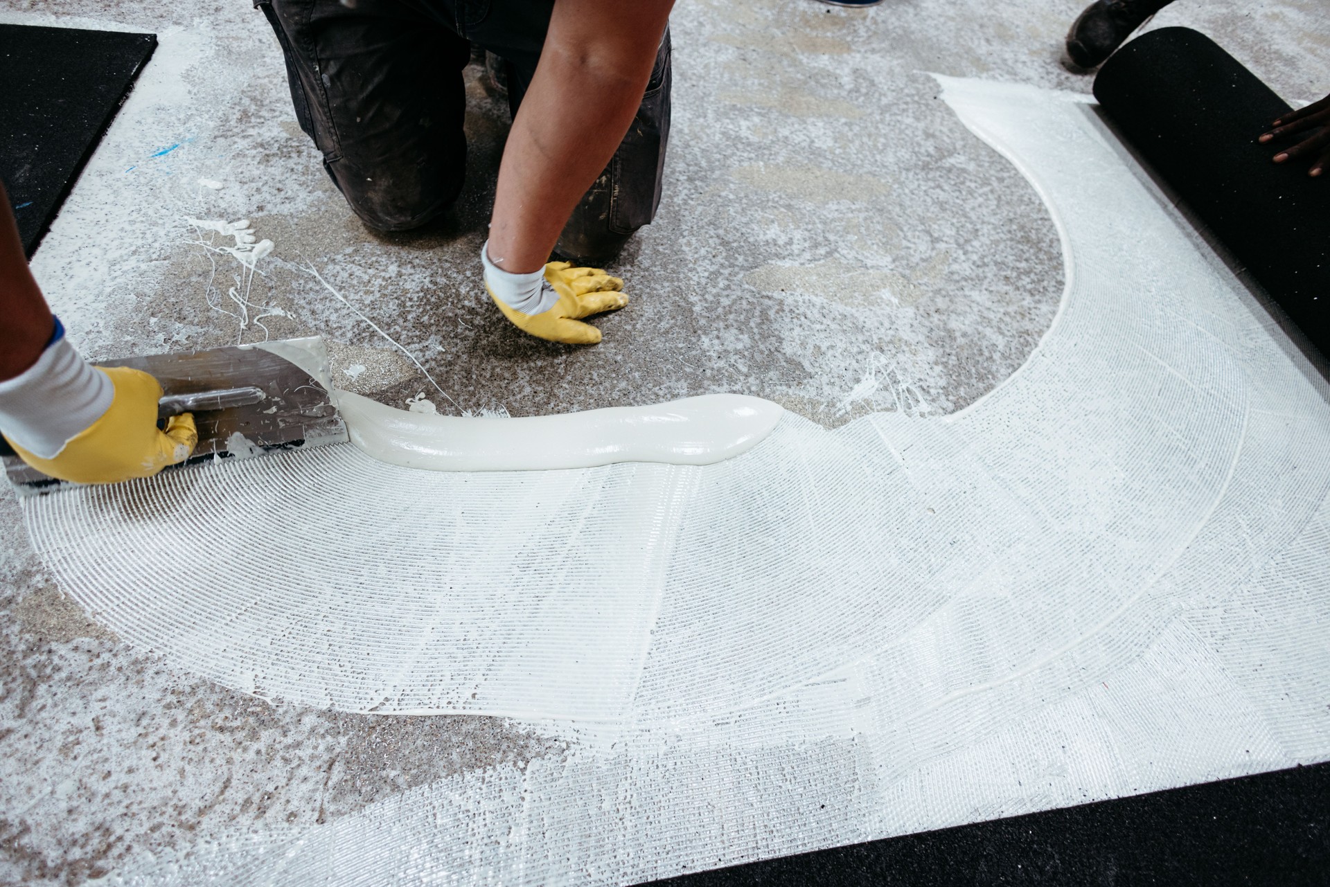 Construction workers applying waterproofing tape and primer on the floor